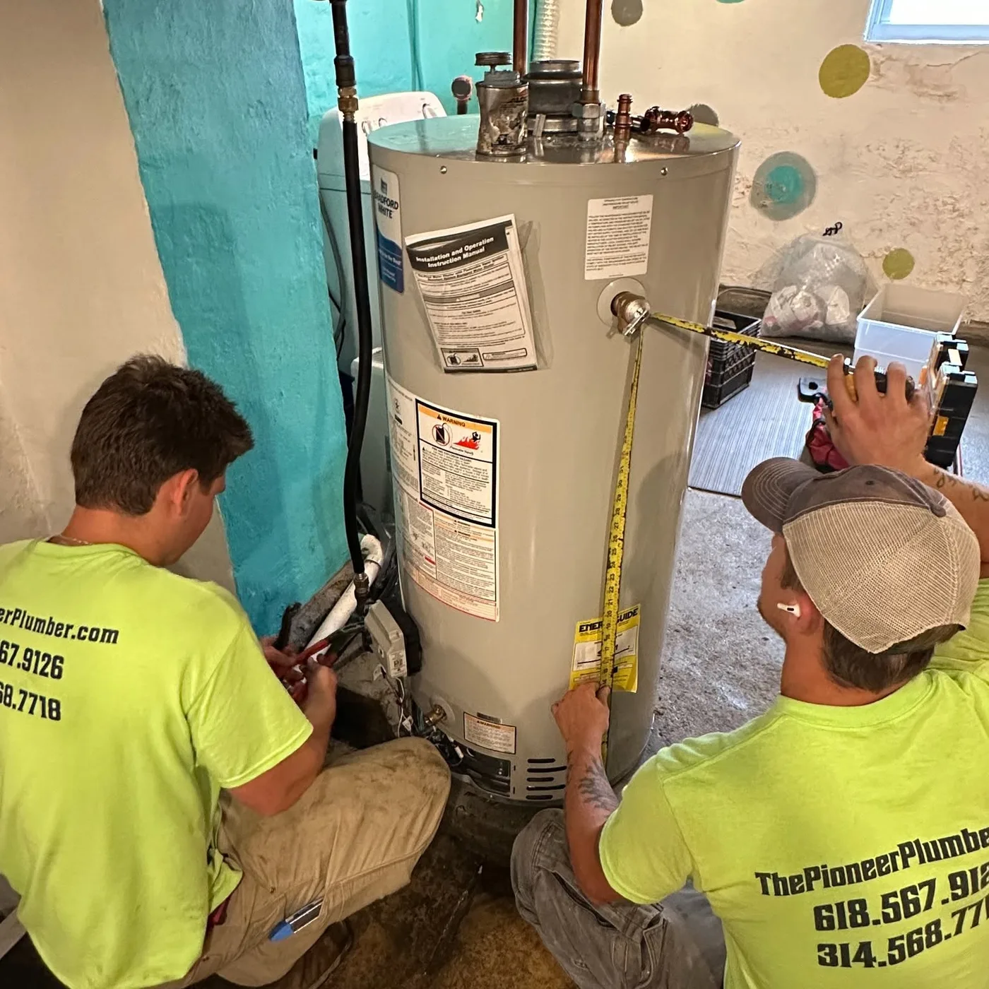 Two Pioneer technicians measuring piping beside a residential water heater