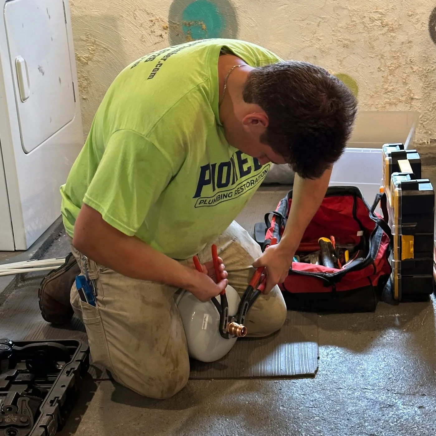 Pioneer technician preparing a fitting during a residential water-heater installation