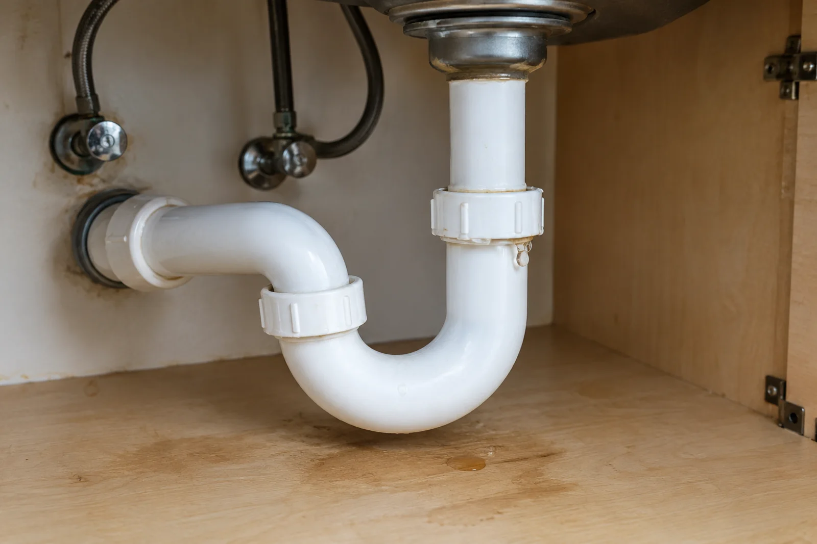 Kitchen sink drain and trap connection beneath a cabinet