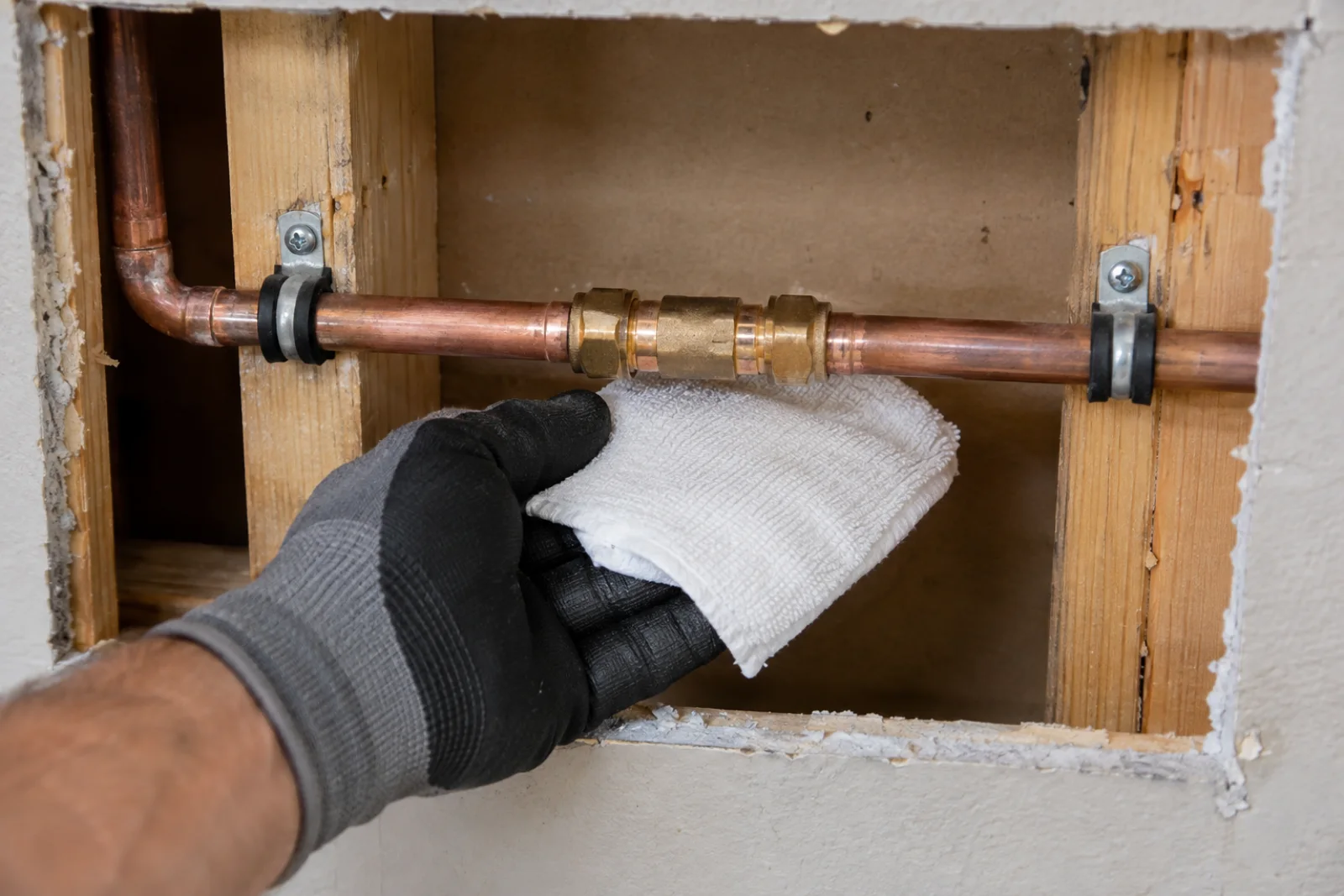 Plumber checking a newly repaired and supported section of residential copper piping